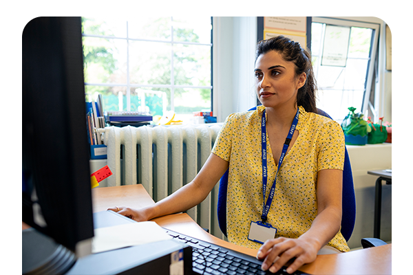 Female teacher sitting in classroom with computer